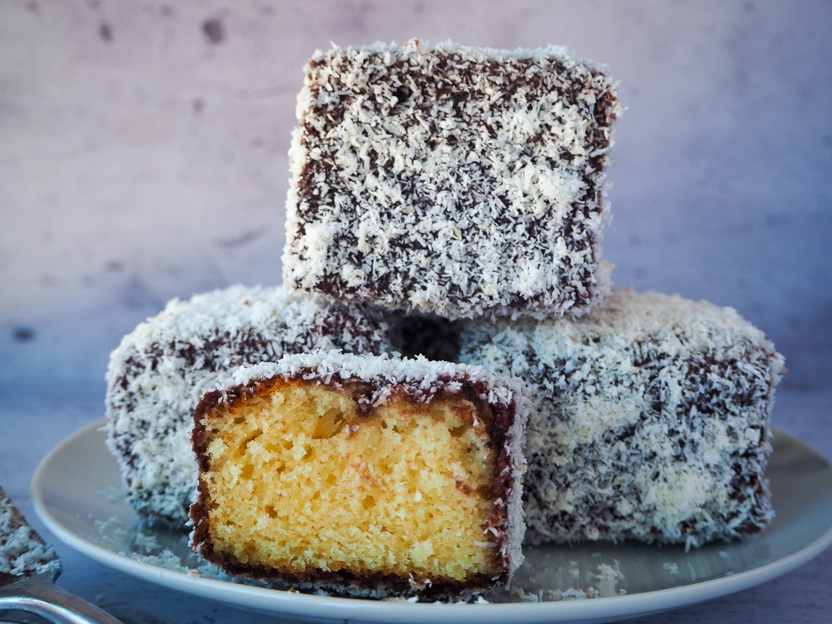 Stack of three lamingtons with a lamington cut open in front.