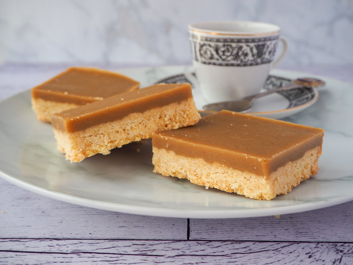 Pieces of ginger crunch with a coffee cup and spoon.