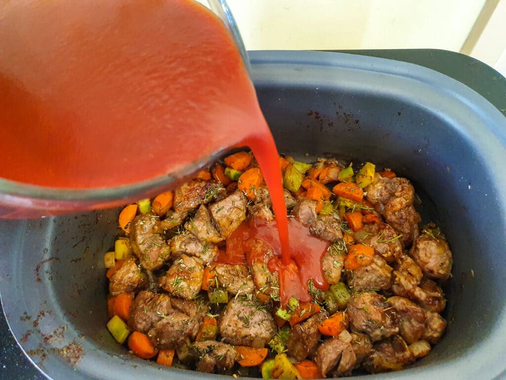 Slow cooker lamb ragu 24 Pouring sauce over other ingredients.