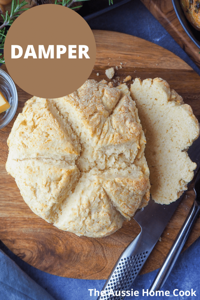 Cut damper on a chopping board with butter, bread knife and dishes on the sides, beetroot salad, mini roasted potatoes and slow cooker lam shoulder with text overlay, Damper and The Aussie Home Cook.