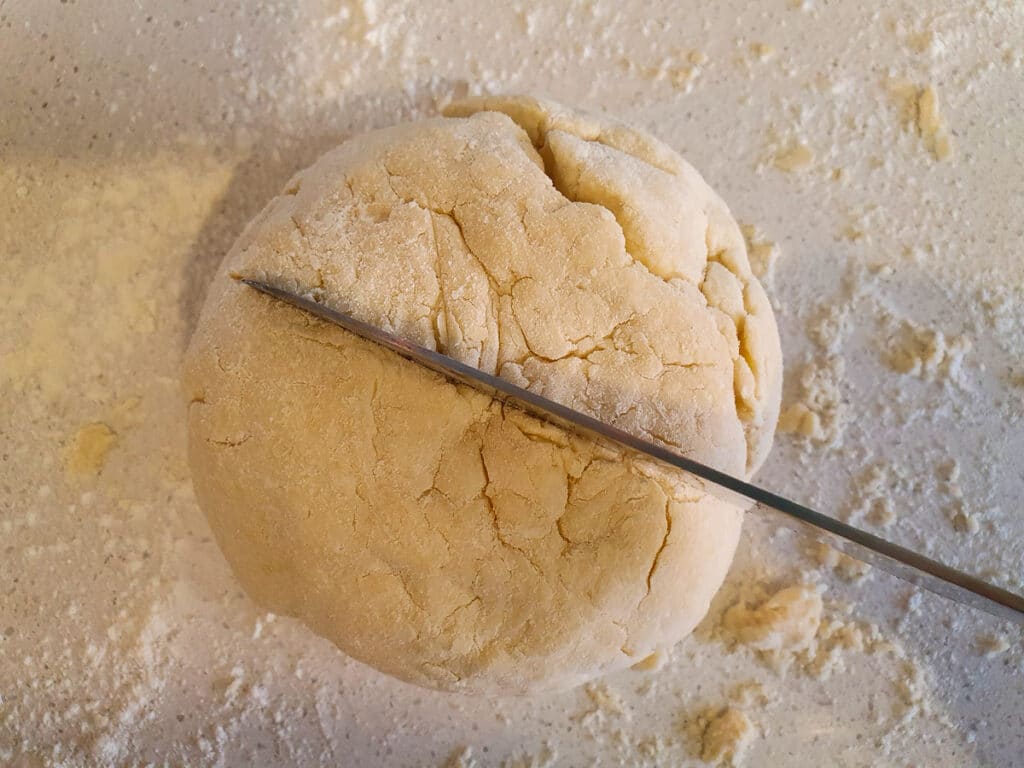 Cutting a shallow star in the top of the dough ball with a sharp knife.