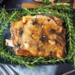 Close up slow cooker lamb roast on a serving plate, garnished with fresh rosemary.
