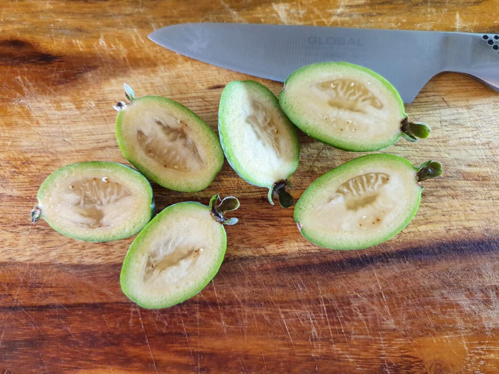 Slicing feijoas in half length ways to scoop out flesh.