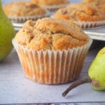 Pear muffins 15 Close up pear muffin with fresh pears and tray of muffins in the background.