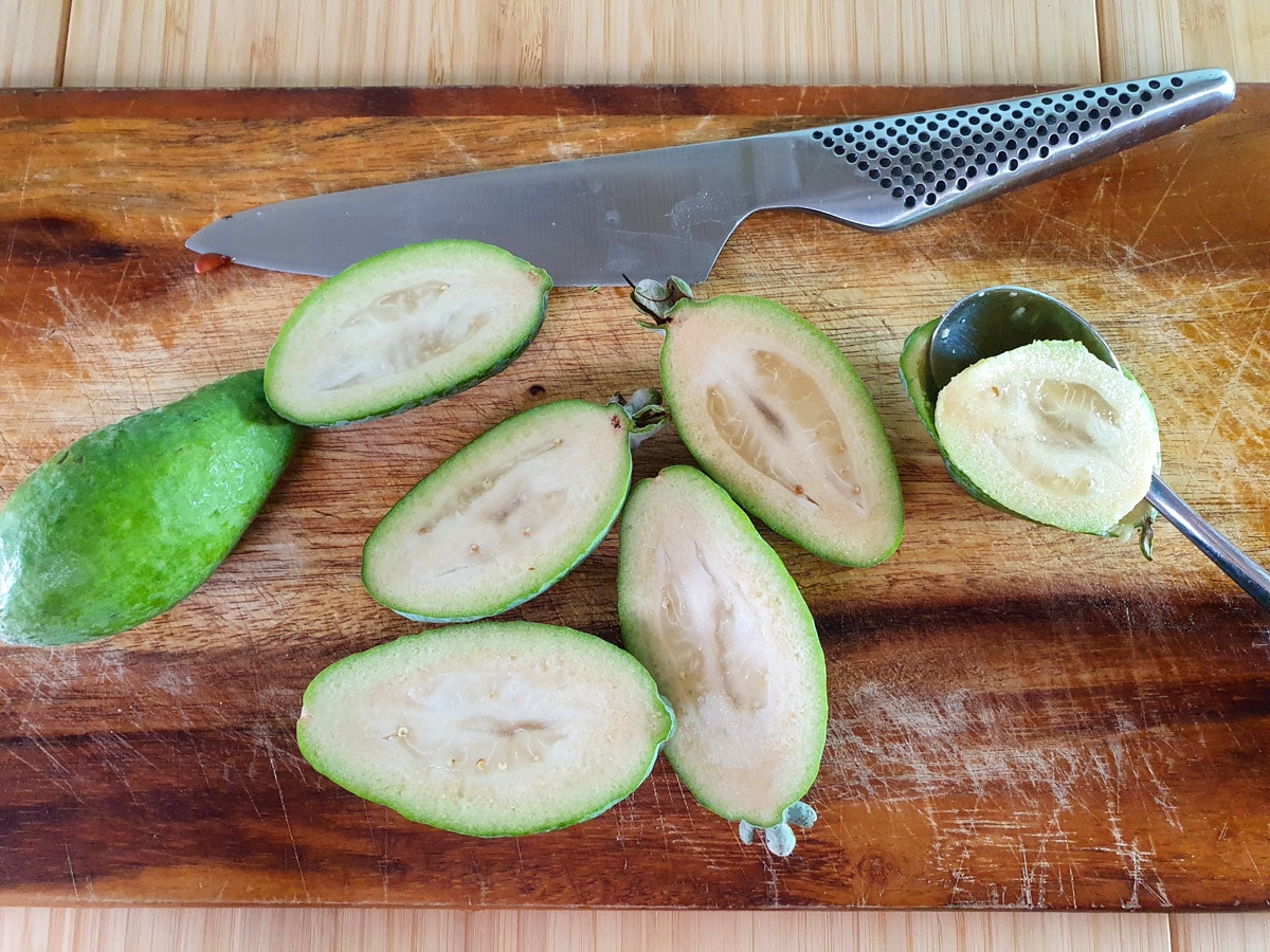 Slicing open feijoas and scooping out flesh.