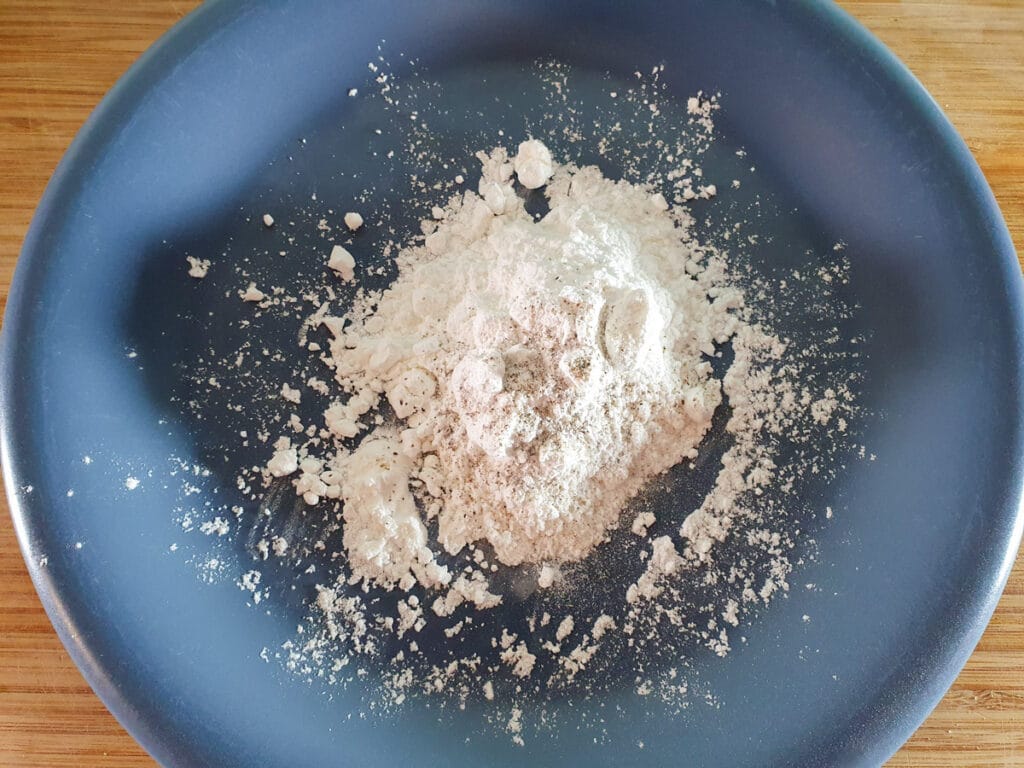 Put the corn flour onto a plate and season it.