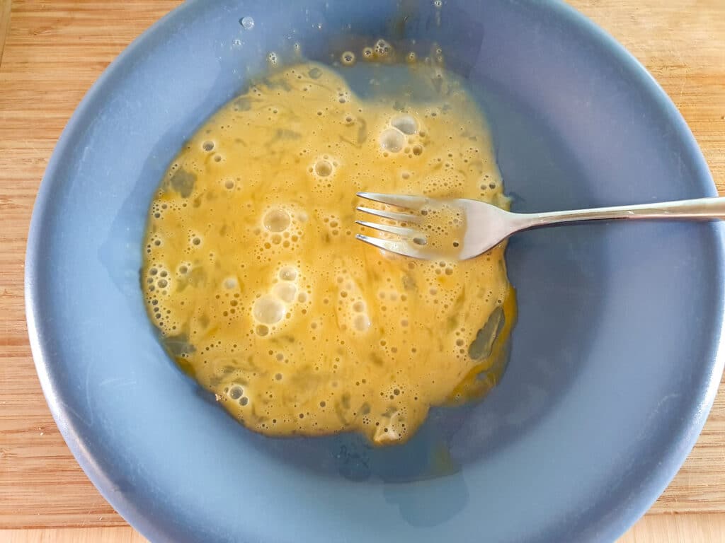 Lightly beating egg on a plate.
