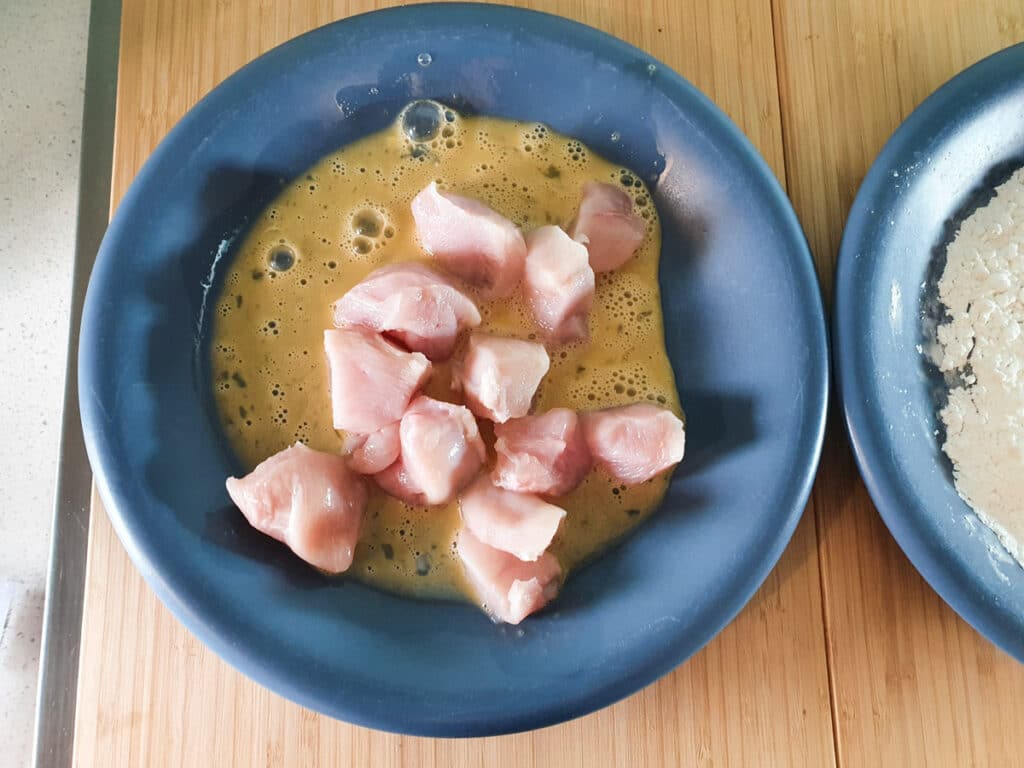Dipping chicken into egg wash.