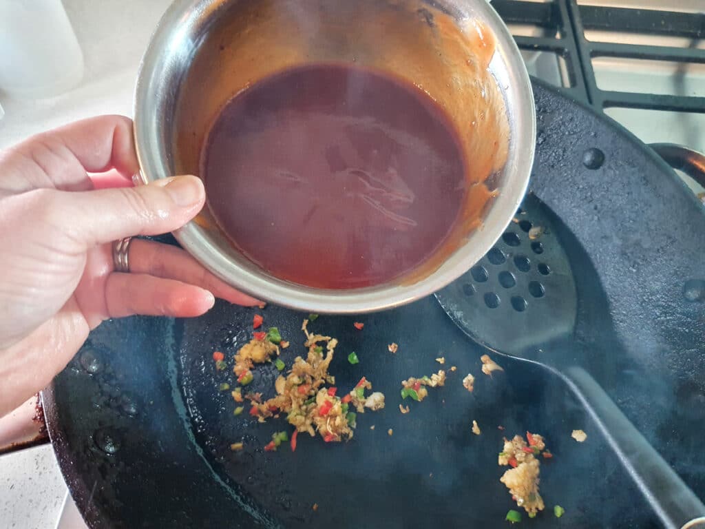 Adding tomato sauce mix to the pan.