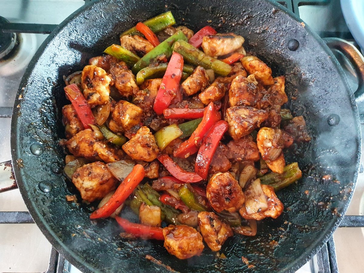 Stirring to coat chicken and vegies in sauce.