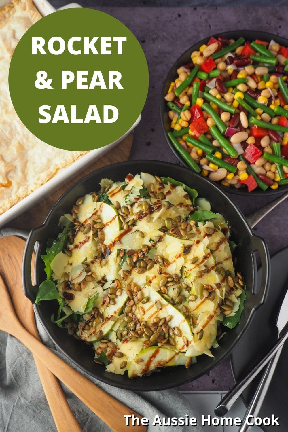 Salads with serving spoons and four bean salad and pie in the background, with text overlay, rocket and pear salad and The Aussie Home Cook.