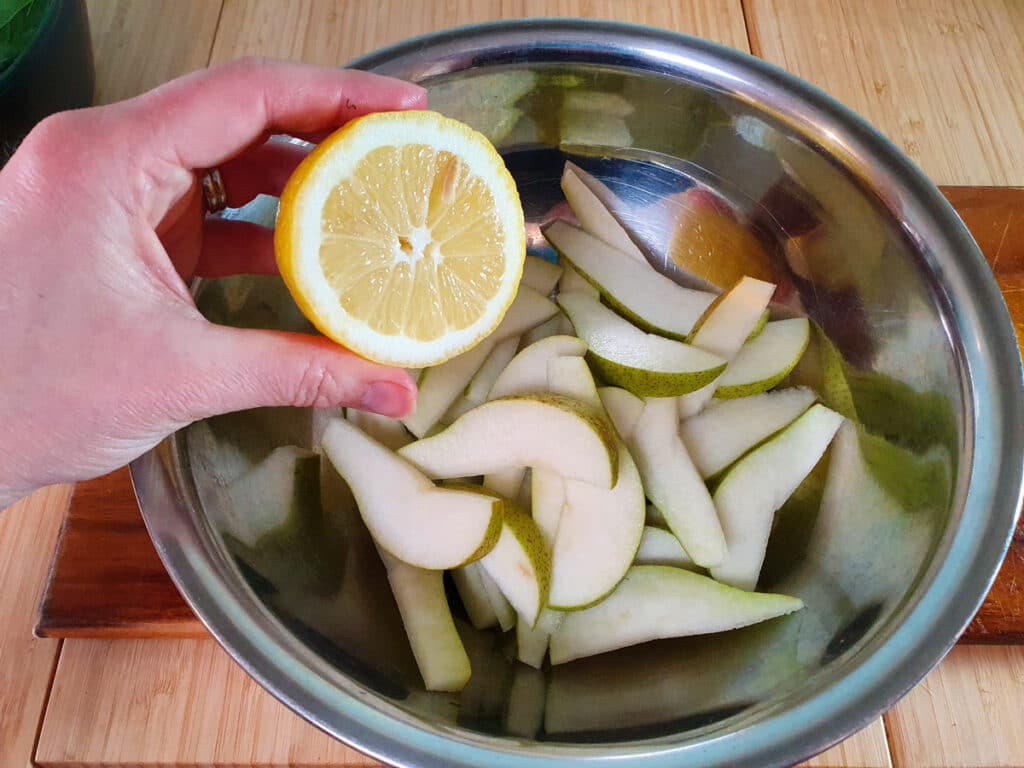 Squeezing lemon juice over sliced pears.