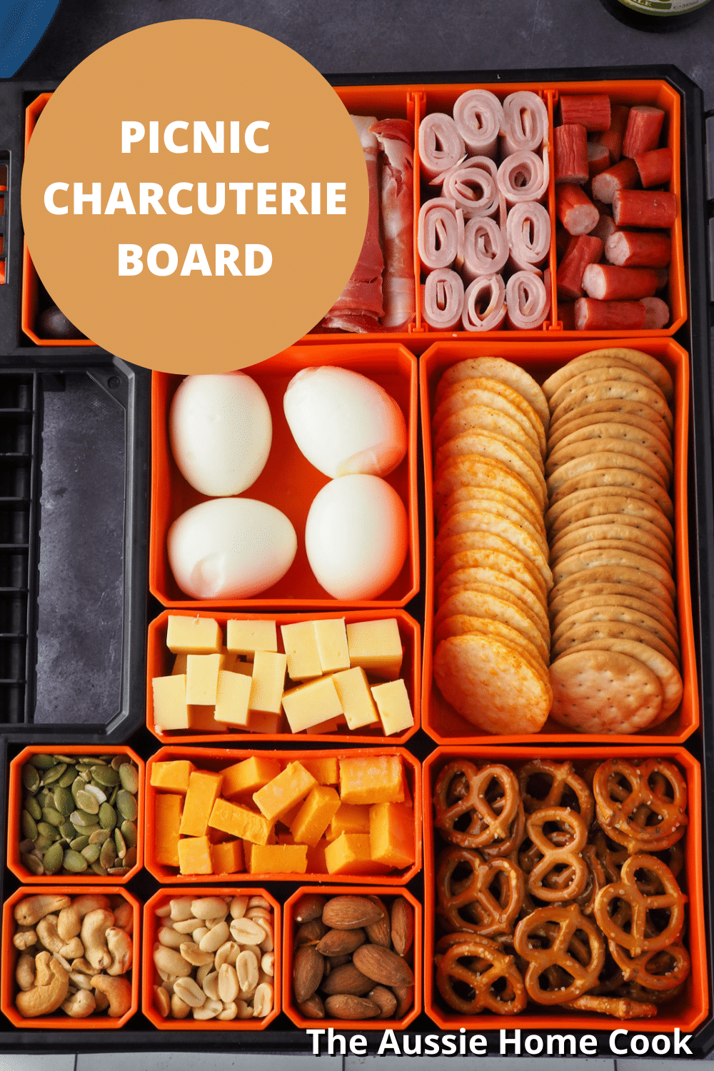 Picnic Charcuterie Board 12 Close up of mulit compartment container filled with various charcuterie food items, with text overlay, picnic charcuterie board and The Aussie Home Cook.