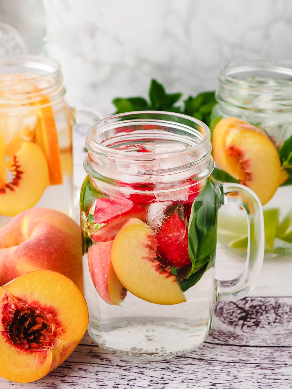 Peach Water 11 Peach infused water with strawberry and basil, with lime mint mixins and orange ginger mixins in background.