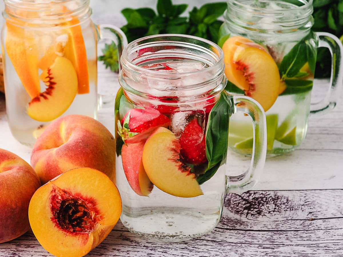 Peach Water 1 Peach infused water with strawberry and basil, with lime mint mixins and orange ginger mixins in background.