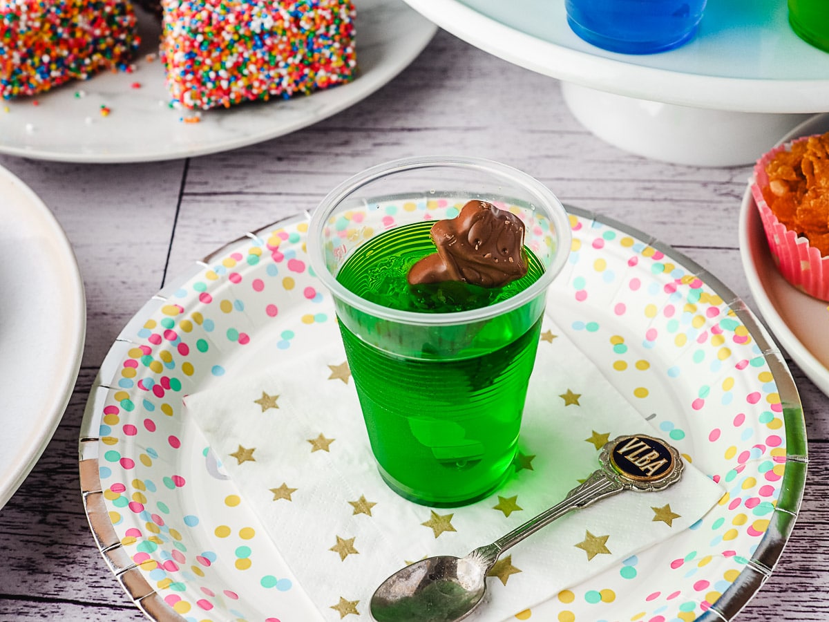 Jelly cup on a party plate with a spoon and party food in the background.
