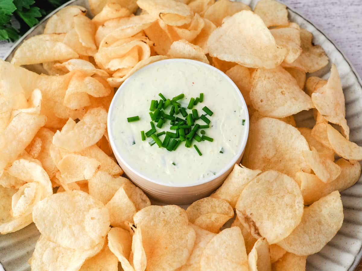 Sour cream dip on a serving plate surrounded by chips.